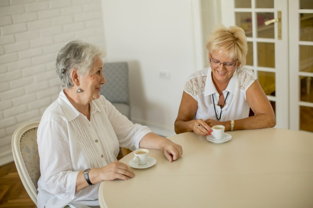 Two older women drinking coffe at home and talking